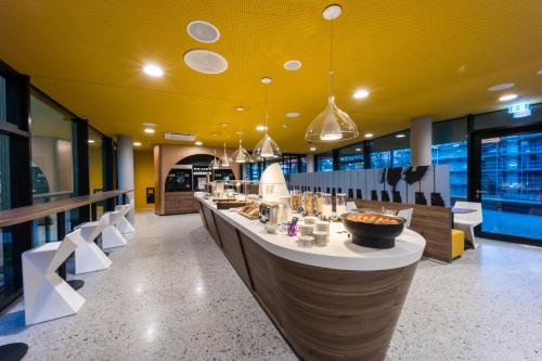 a restaurant with a long bar with chairs and tables at Prize by Radisson, Bonn City in Bonn