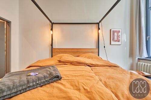 ein Bett mit einer orangefarbenen Bettdecke in einem Zimmer in der Unterkunft casanando prestige Suites - HiFi Erlebnis in Zoo - und Citylage in Leipzig