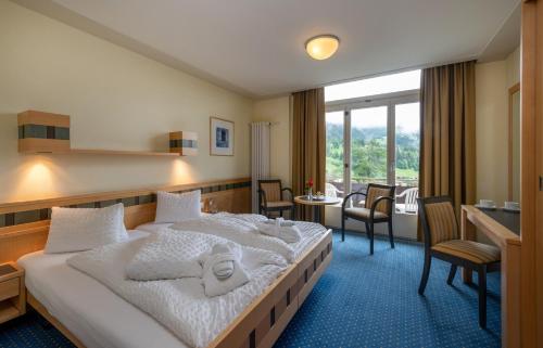 ヴェンゲンにあるArenas Resort Victoria-Lauberhornのベッド、テーブル、椅子が備わるホテルルームです。