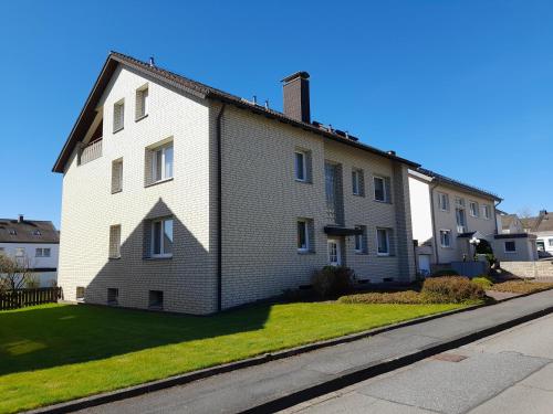 a white brick house on the side of a street at Ferienwohnung und Gästezimmer Iburgblick in Bad Driburg