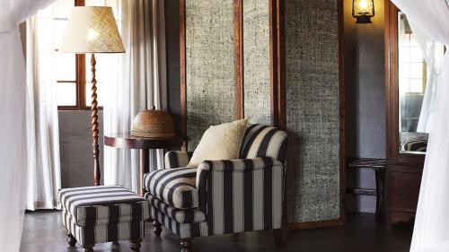 a living room with a chair and a stool at Motswari Private Game Reserve by NEWMARK in Timbavati Game Reserve