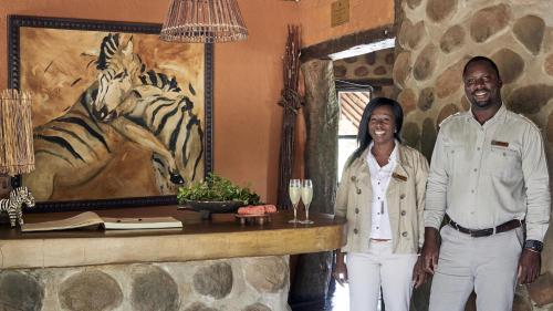 a man and a woman standing in a room with a painting of zebras at Motswari Private Game Reserve by NEWMARK in Timbavati Game Reserve