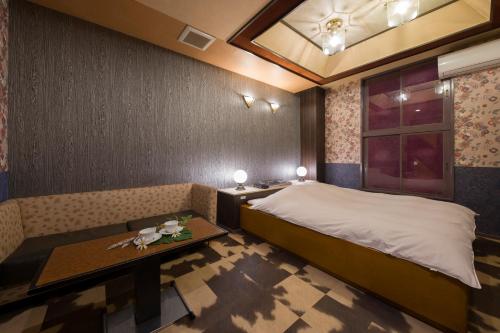 a bedroom with a bed and a table and a window at Hotel ニャンだふる in Himeji