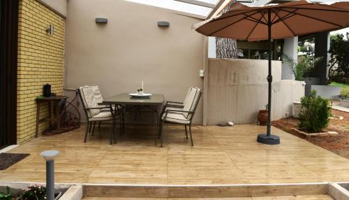 a patio with a table and chairs and an umbrella at Amazing Garden House in Athens