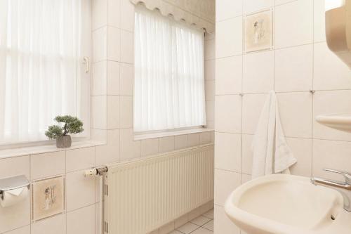 een witte badkamer met een wastafel en een toilet bij Ferienwohnung Muschelblume mit Terrasse im Kaiserhof 3 in Kellenhusen