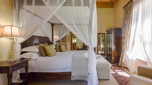 a bedroom with a canopy bed with white sheets and pillows at Mount Camdeboo Private Game Reserve by NEWMARK in Graaff-Reinet