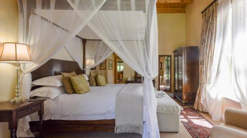 a bedroom with a canopy bed with white sheets and pillows at Mount Camdeboo Private Game Reserve by NEWMARK in Graaff-Reinet