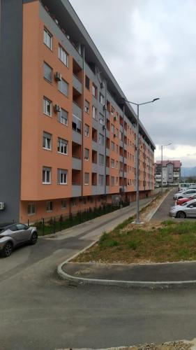an apartment building with cars parked in a parking lot at Apartman Andrej in Vranješ