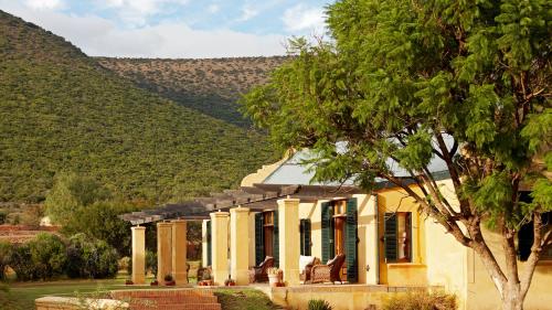 a yellow house with a mountain in the background at Mount Camdeboo Private Game Reserve by NEWMARK in Graaff-Reinet