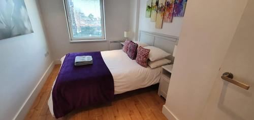 a bedroom with a bed with a purple blanket on it at Bright & spacious Double Bedroom with EnSuite and Concierge! Paid parking available in London