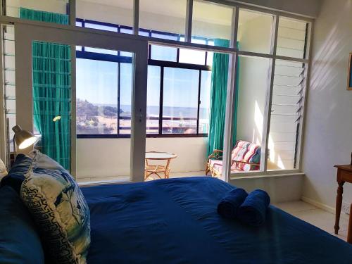 a bedroom with a blue bed and large windows at Claridges 104 in Margate