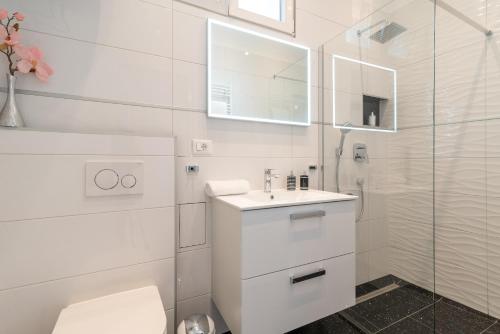 a white bathroom with a sink and a shower at Apartment Silvia in Trogir