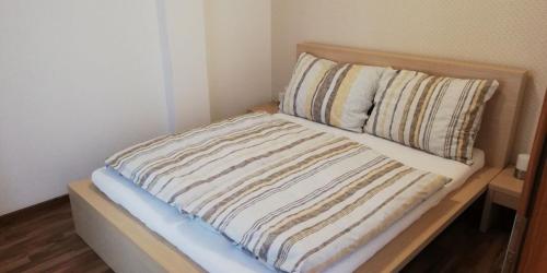 a bed with a striped comforter and two pillows at Oliver apartmán 6 in Vysoke Tatry - Strbske Pleso