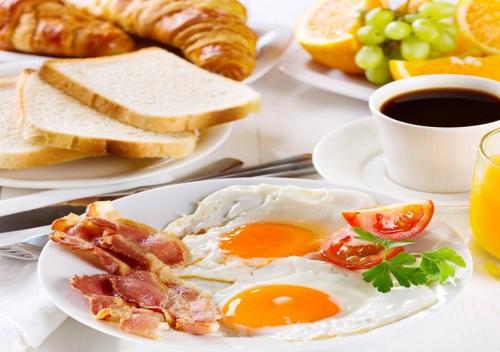 a breakfast plate with eggs bacon and toast and coffee at Kuwait Grand Hotel in Kuwait