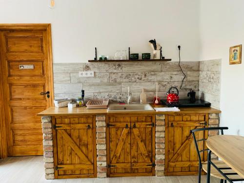 una cocina con armarios de madera y fregadero en Kata Cottage, en Szanda