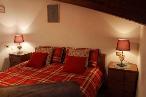 1 dormitorio con 1 cama con almohadas rojas y 2 lámparas en All'Ombra del Mortirolo, en Mazzo di Valtellina