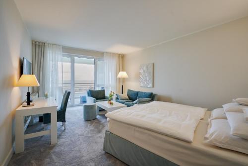 a bedroom with a bed and a living room at Strandhotel Dünenmeer - Adults only in Dierhagen