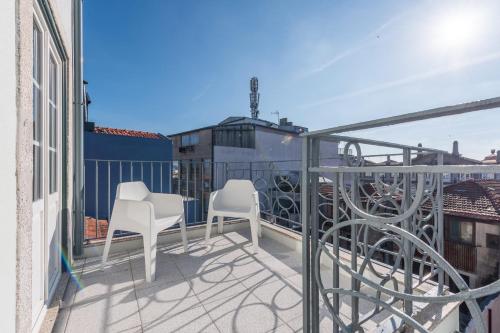 a balcony with two white chairs on a building at Sá de Noronha Mezzanine w Terrace in Porto