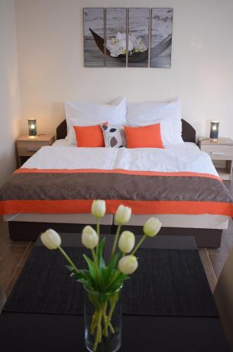 a bedroom with a bed with a vase of flowers at Elixír Apartman in Villány