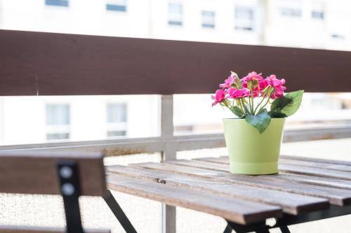 a pot of pink flowers sitting on a wooden bench at GuestReady - The Happy Place in Porto in Porto