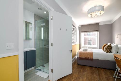 a bedroom with a bed and a glass shower at 37 Doughty Street - Urban Apartments in London