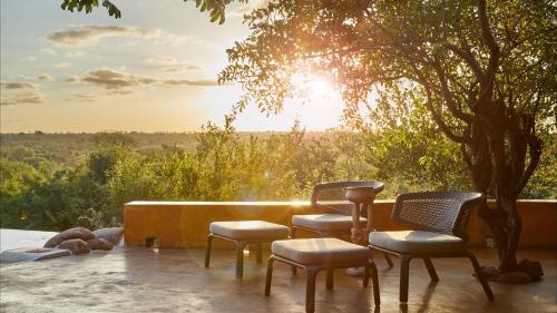 a group of chairs sitting in front of a tree at Geiger's Camp in Timbavati Game Reserve by NEWMARK in Timbavati Game Reserve