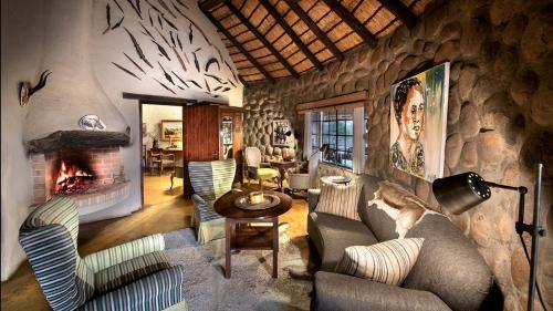 a living room with a stone wall with a fireplace at Geiger's Camp in Timbavati Game Reserve by NEWMARK in Timbavati Game Reserve