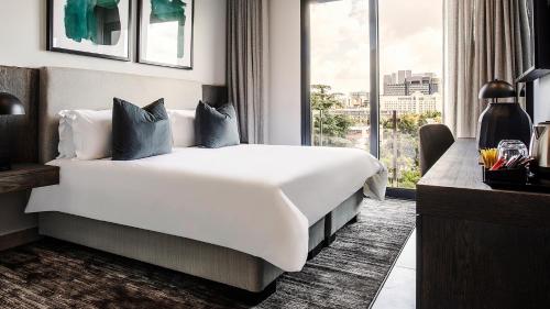 a bedroom with a large white bed and a window at The Catalyst Apartment Hotel by NEWMARK in Johannesburg