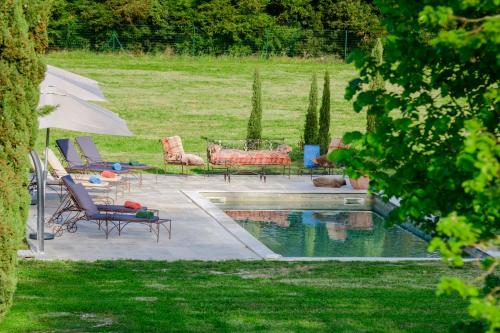 a backyard with a pool with chairs and an umbrella at Bastide de Bellegarde in Avignon