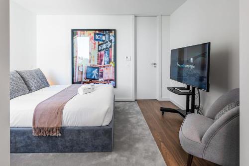 a bedroom with a bed and a tv and a chair at Marques Design Apartments in Porto