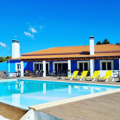 a villa with a swimming pool and yellow chairs at Herdade Monte Novo Do Pocinho in Cercal