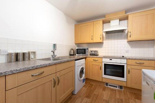 een keuken met houten kasten, een wastafel en een vaatwasser bij BEST PRICE! Superb city centre apartment, 2 Superkings or 4 singles Smart TV & Sofa bed- FREE SECURE PARKING in Southampton