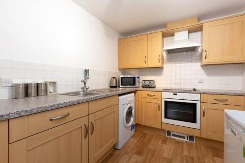 a kitchen with wooden cabinets and a sink and a dishwasher at BEST PRICE! Superb city centre apartment, 2 Superkings or 4 singles Smart TV & Sofa bed- FREE SECURE PARKING in Southampton