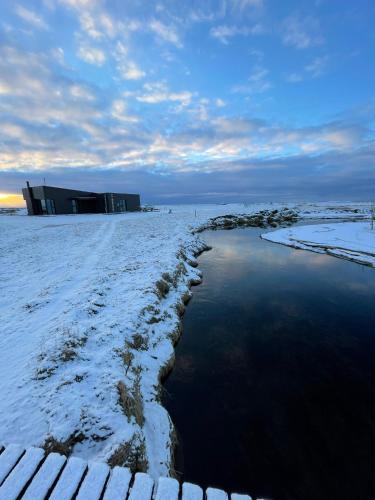 a building in the snow next to a body of water at Fögruvellir Country House in Hella