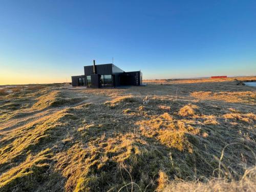 a small black building in a field with grass at Fögruvellir Country House in Hella