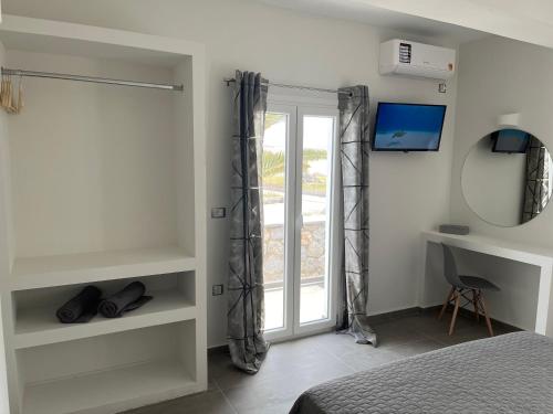 een slaapkamer met een bed, een raam en een bureau bij Ether in Perivolos