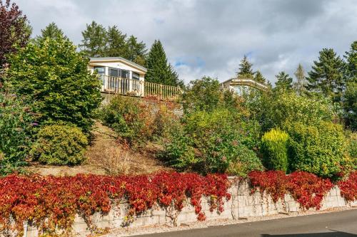 a house with a bunch of flowers on a retaining wall at Corriefodly Holiday Park in Blairgowrie