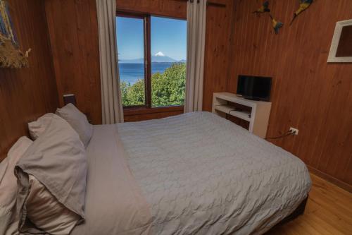 a bedroom with a bed and a large window at Bordemundo B&B y Cabañas in Puerto Varas