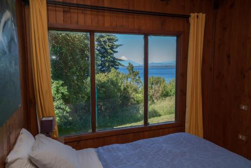 a bedroom with a large window with a view of the water at Bordemundo B&B y Cabañas in Puerto Varas