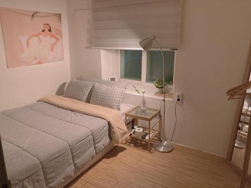 1 dormitorio con cama, ventana y lámpara en Yakorea Hostel Dongdaemun, en Seúl