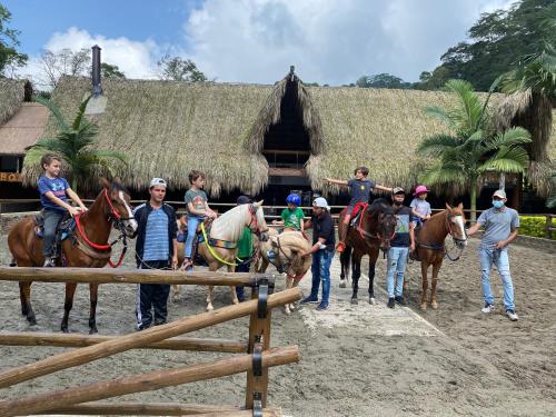 a group of people riding horses in front of a hut at Rancho Ecoturistico el Faro in La Mesa