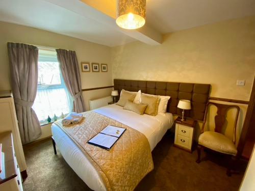 a bedroom with a large bed and a chair at Rowan Tree Guest House in Keswick