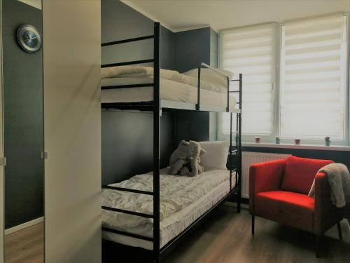 een slaapkamer met 2 stapelbedden en een rode stoel bij Nadmorski Zojka-Apartament Gdańsk in Gdańsk