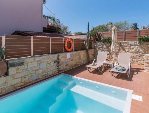 a swimming pool with two chairs next to a house at Villa Olive Tree in Pitsidia