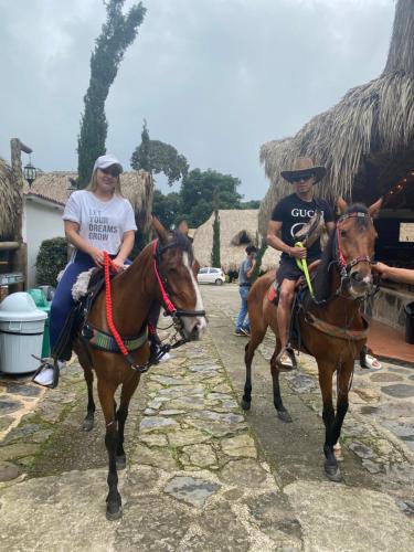 two people are riding horses down a street at Rancho Ecoturistico el Faro in La Mesa