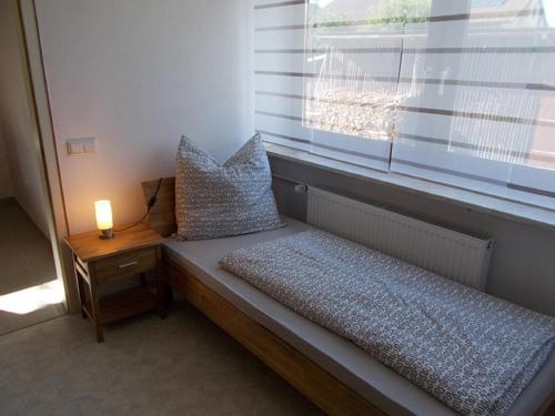 een bed in een kamer met een raam met een lamp bij Ferienwohnung Familie Bauer in Kelheim