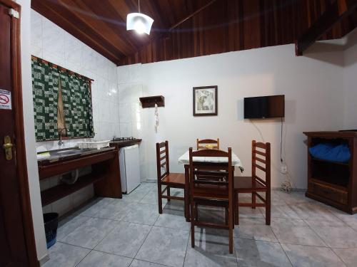 a kitchen with a table and chairs and a sink at Pousada Canto do Curió Paraty in Paraty