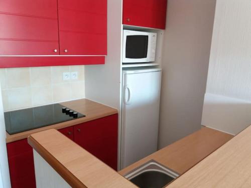 a kitchen with red cabinets and a refrigerator with a microwave at Maison de vacances pour détente dans résidence familiale avec prêt de vélos in Monflanquin