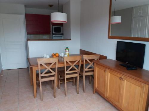 a kitchen with a table with chairs and a television at Maison de vacances pour détente dans résidence familiale avec prêt de vélos in Monflanquin