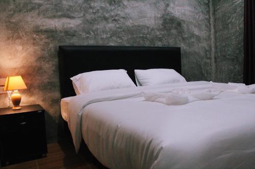a bedroom with a large white bed and a lamp at บ้านทองสุข รีสอร์ท in Ban Dao Ruang